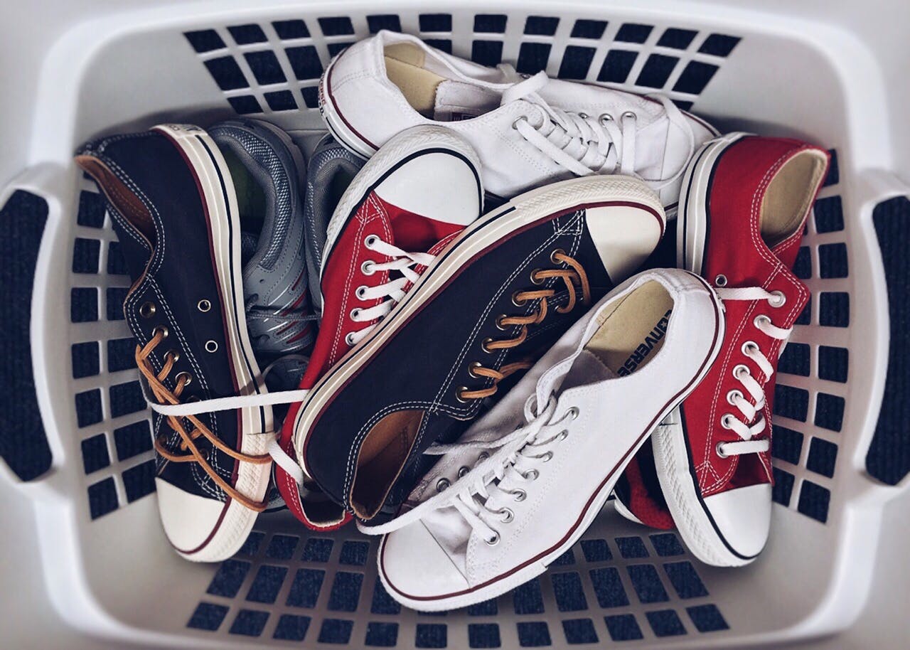 services-04 A variety of vintage sneakers piled in a white laundry basket. Perfect mix of style and nostalgia.