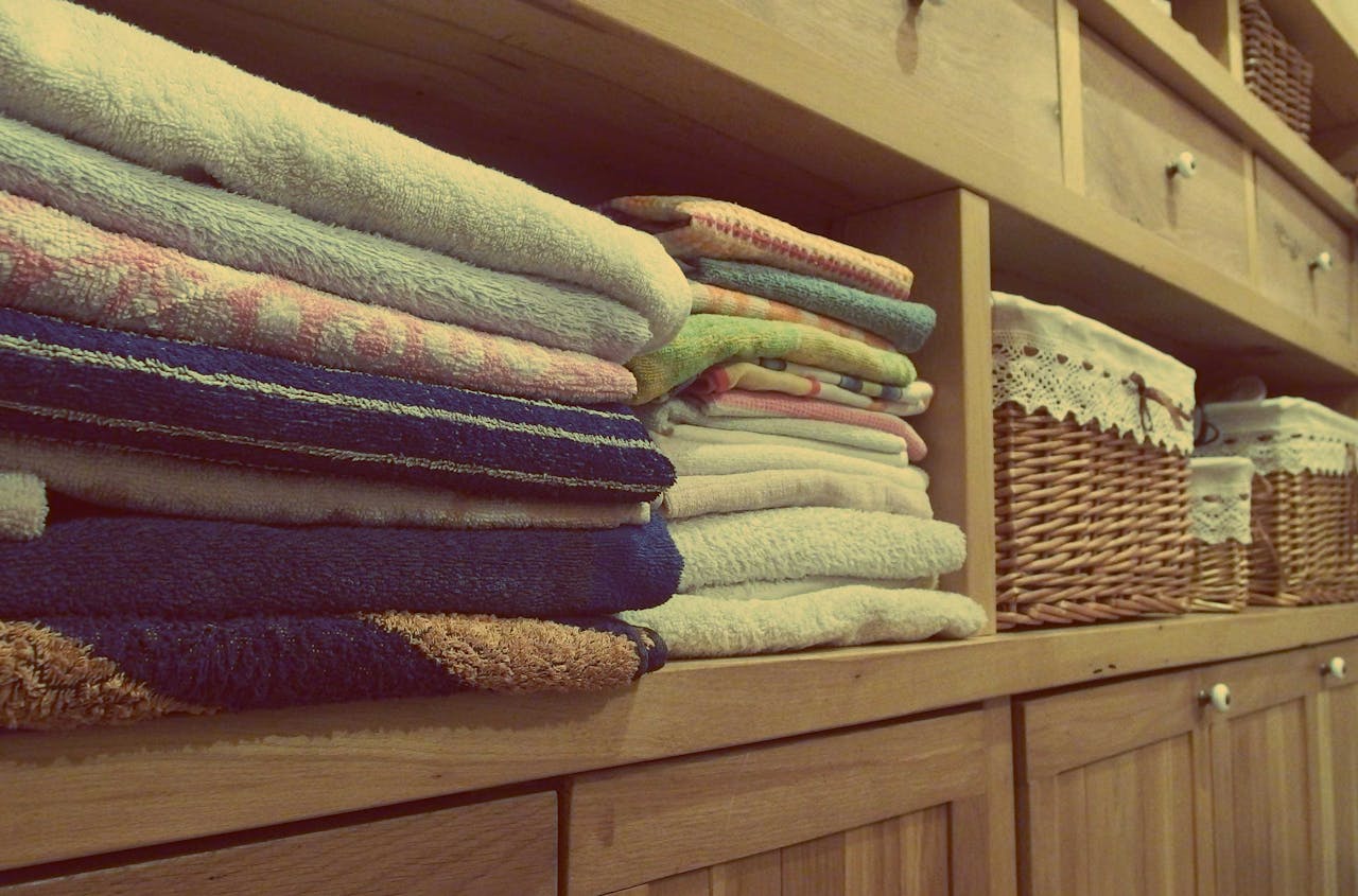 services-03 Tidy wooden cabinet with neatly stacked towels and decorative baskets in an indoor setting.