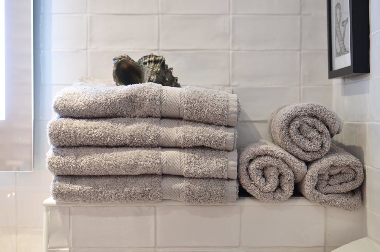A neatly arranged stack of soft gray towels in a contemporary bathroom setting, exuding cleanliness.